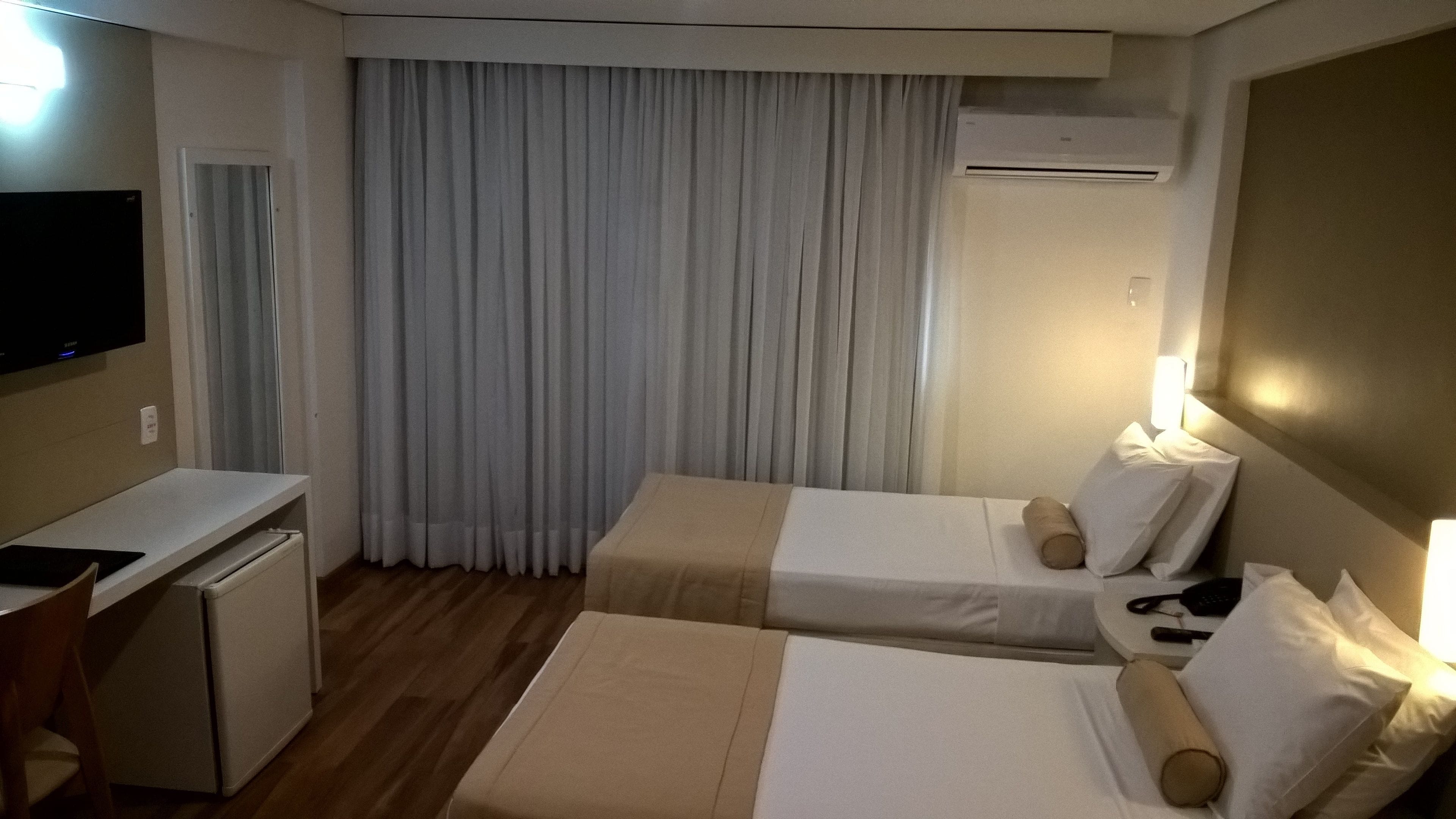 Habitación de hotel con dos camas, un escritorio, un televisor y un equipo de aire acondicionado.