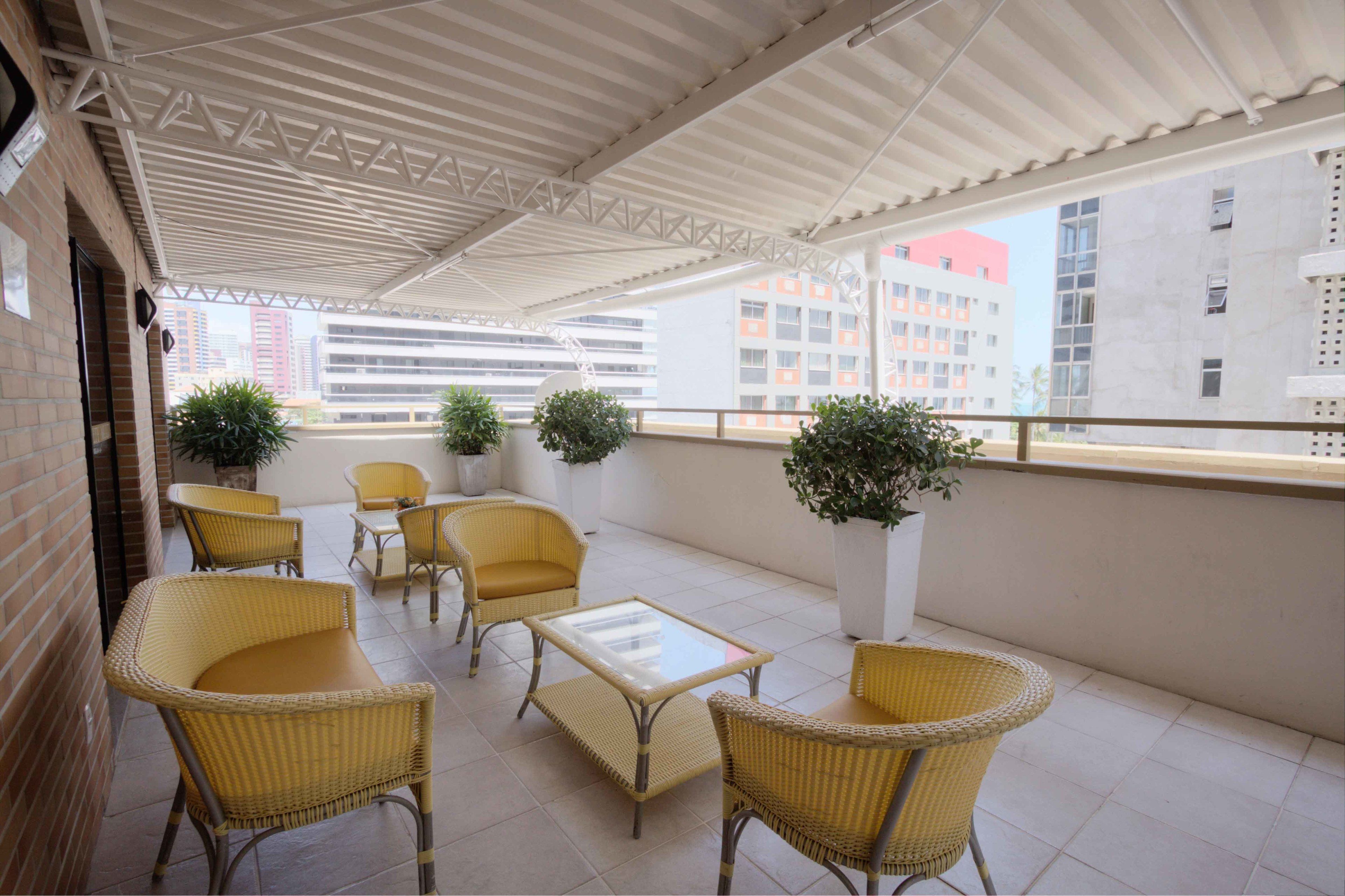 A covered outdoor seating area with wicker furniture and potted plants.