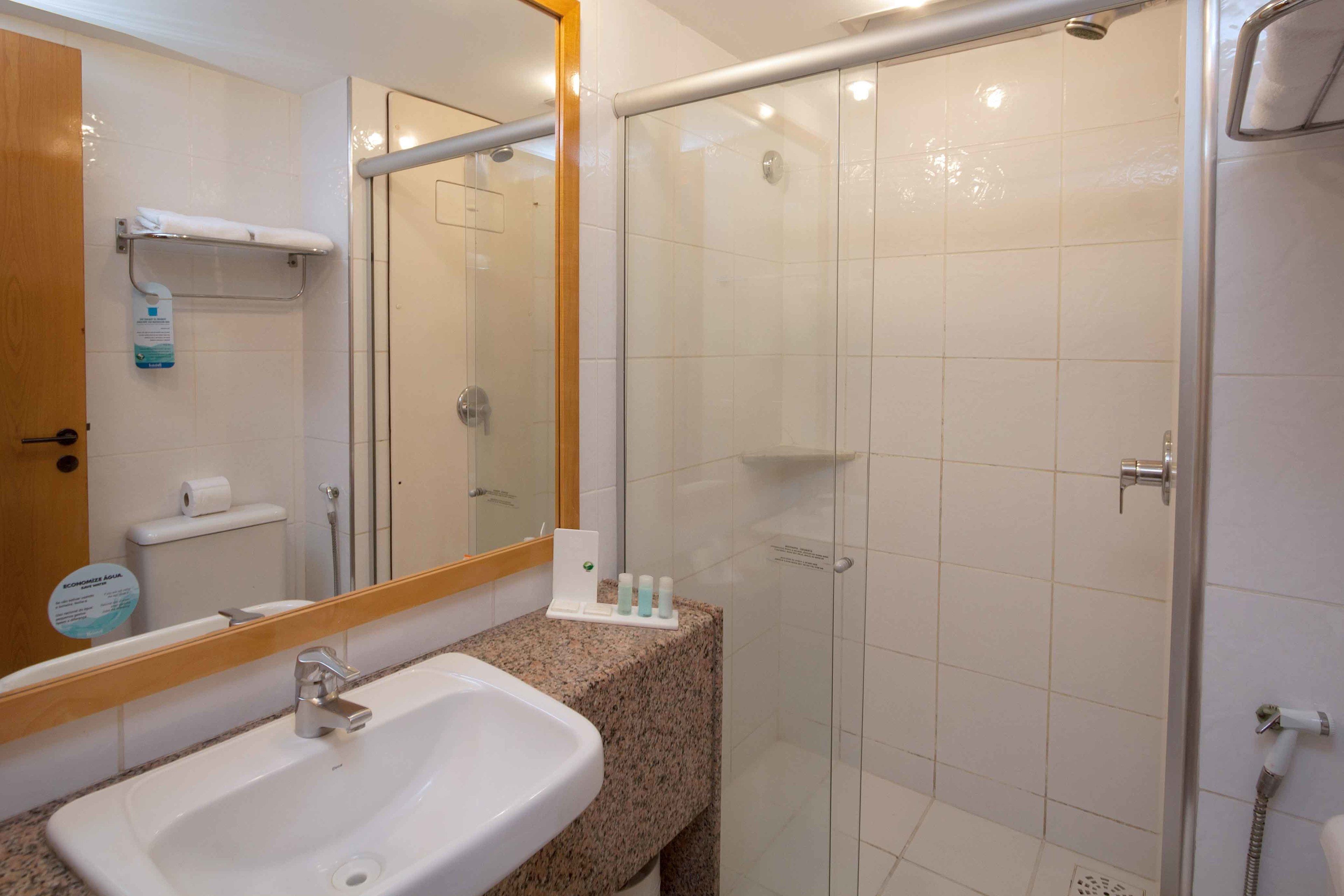 Un baño con lavamanos, espejo, cabina de ducha de vidrio y artículos de aseo en la encimera.