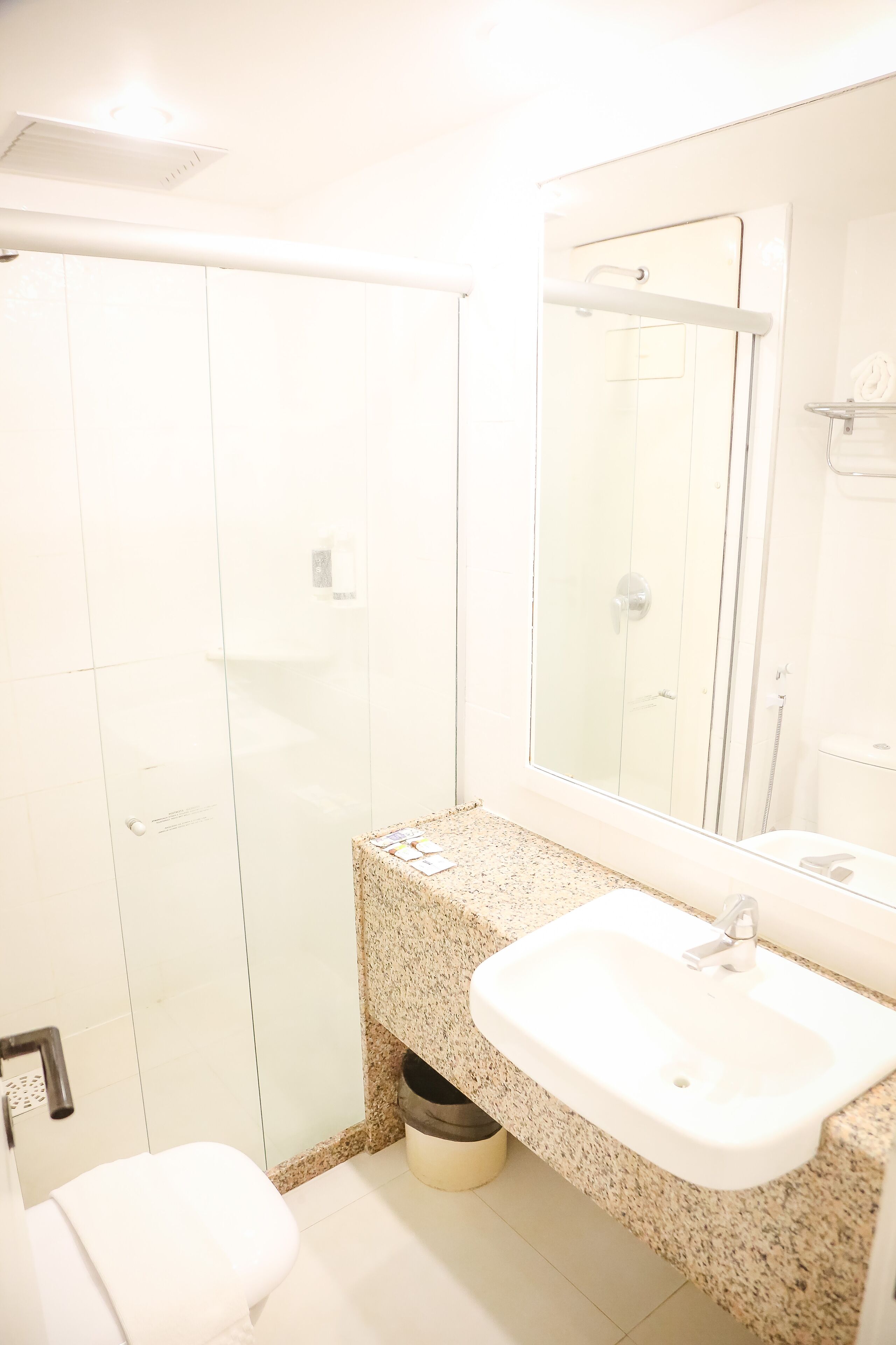 A bathroom with a white sink, a mirror, and a shower enclosure.