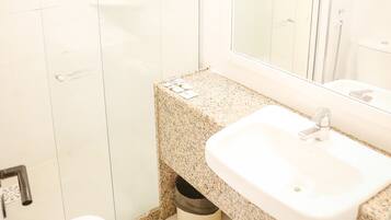 A bathroom with a white sink, a mirror, and a shower enclosure.