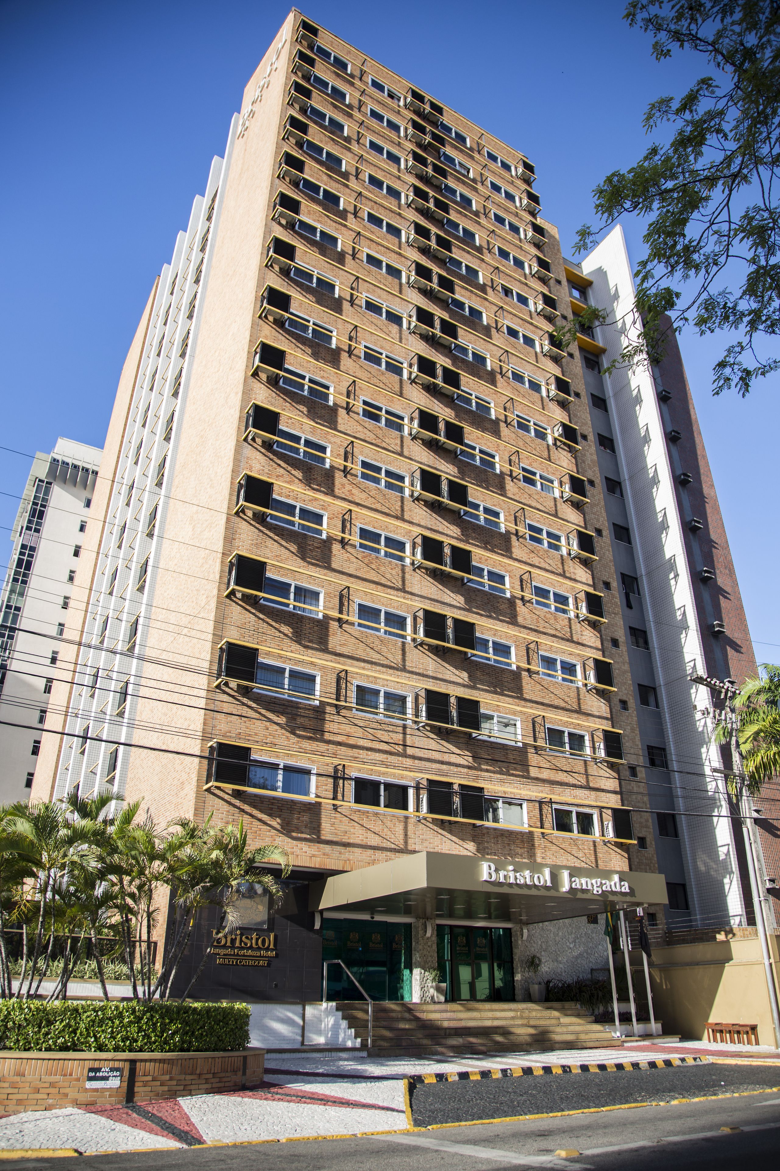 Um hotel alto, com vários andares, e uma entrada notável, com uma placa que diz 'Bristol Jangada'.