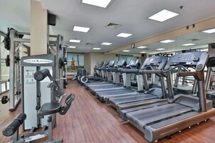 Academia com esteiras, aparelhos de musculação e um espelho grande.