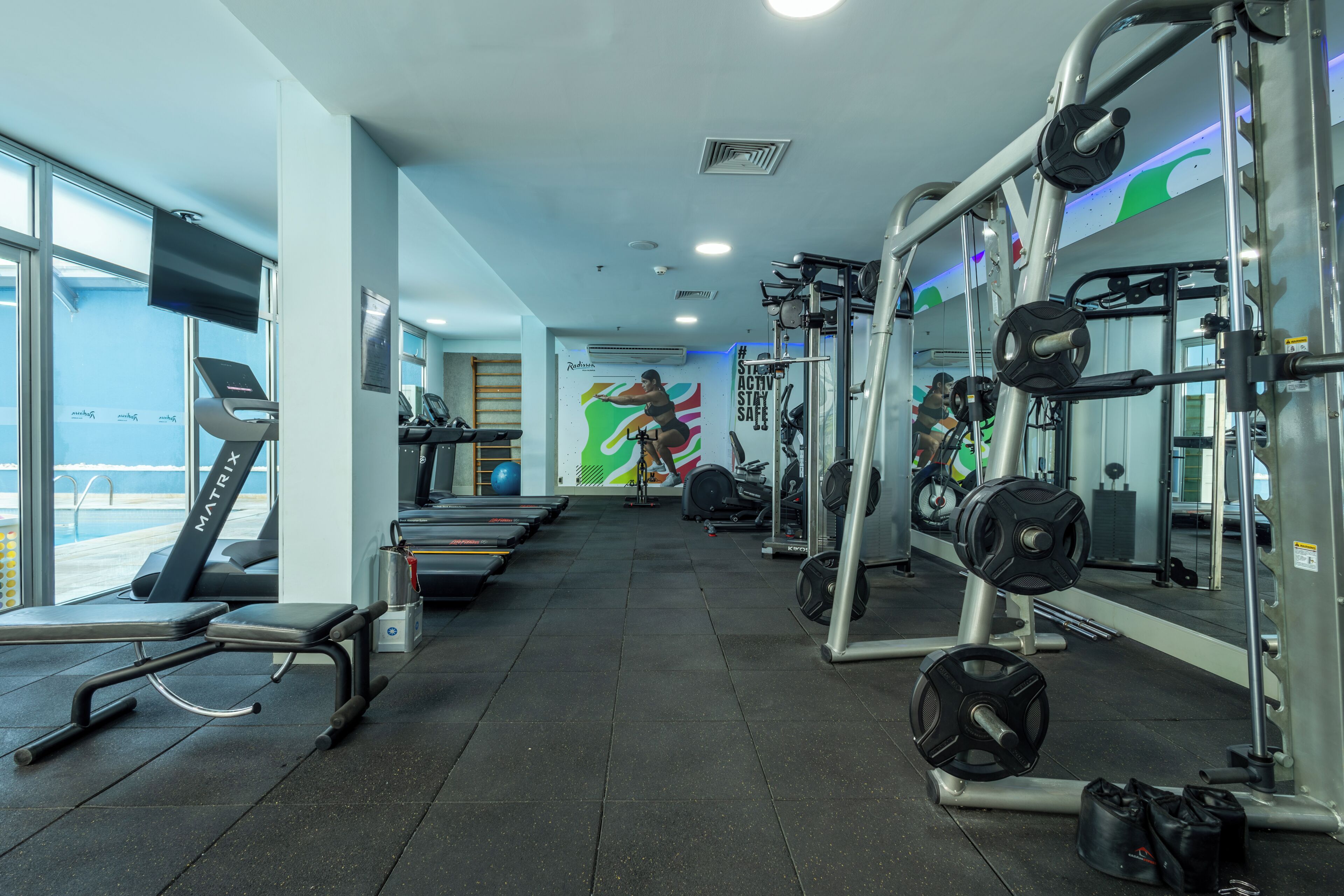Un gimnasio con cintas de correr, máquinas de pesas y un espejo grande.