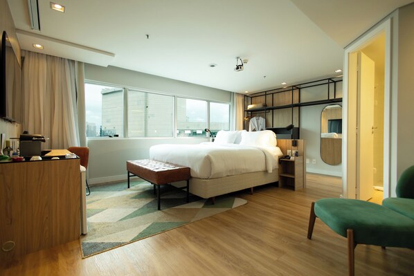 Una habitación de hotel moderna con una cama grande, un escritorio y una zona de estar.