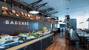 A restaurant with a long counter displaying various dishes, hanging copper pots, and a visible name 'BADEBEC'. - Radisson Hotel Vila Olimpia (São Paulo)