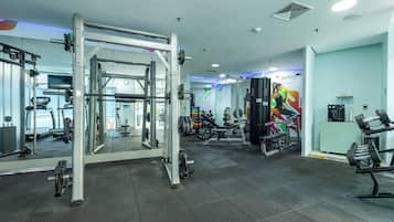 Ett gym med träningsutrustning, speglar och en motivationsaffisch.