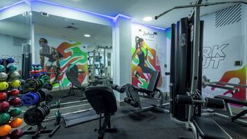 Un gimnasio con equipamiento de levantamiento de pesas, espejos y decoración mural motivacional.