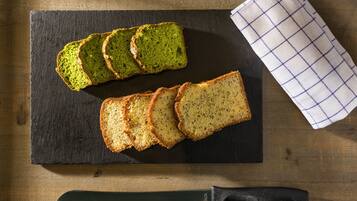 Broodjes van groen en volkorenbrood op een leisteenplank met een mes en een geruit kleed.