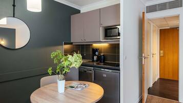 Una cocina moderna con microondas, estufa y lavavajillas. Hay una mesa de comedor con sillas y un jarrón de flores.
