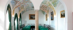 A dining area with a long table set for a meal, arched ceilings with frescoes, and framed artwork on the walls. - Luna Convento (Amalfi)