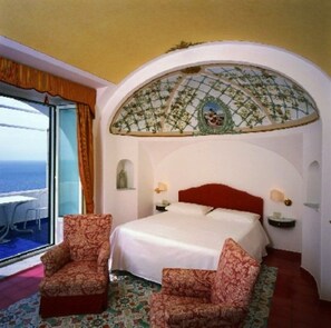 A bedroom with a bed, two chairs, a view of the sea, and a decorative ceiling. - Luna Convento (Amalfi)