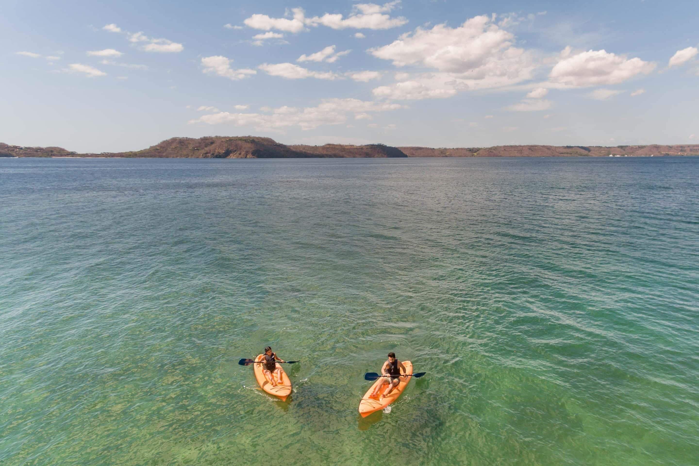 Two kayaks on a calm body of water with clear skies.