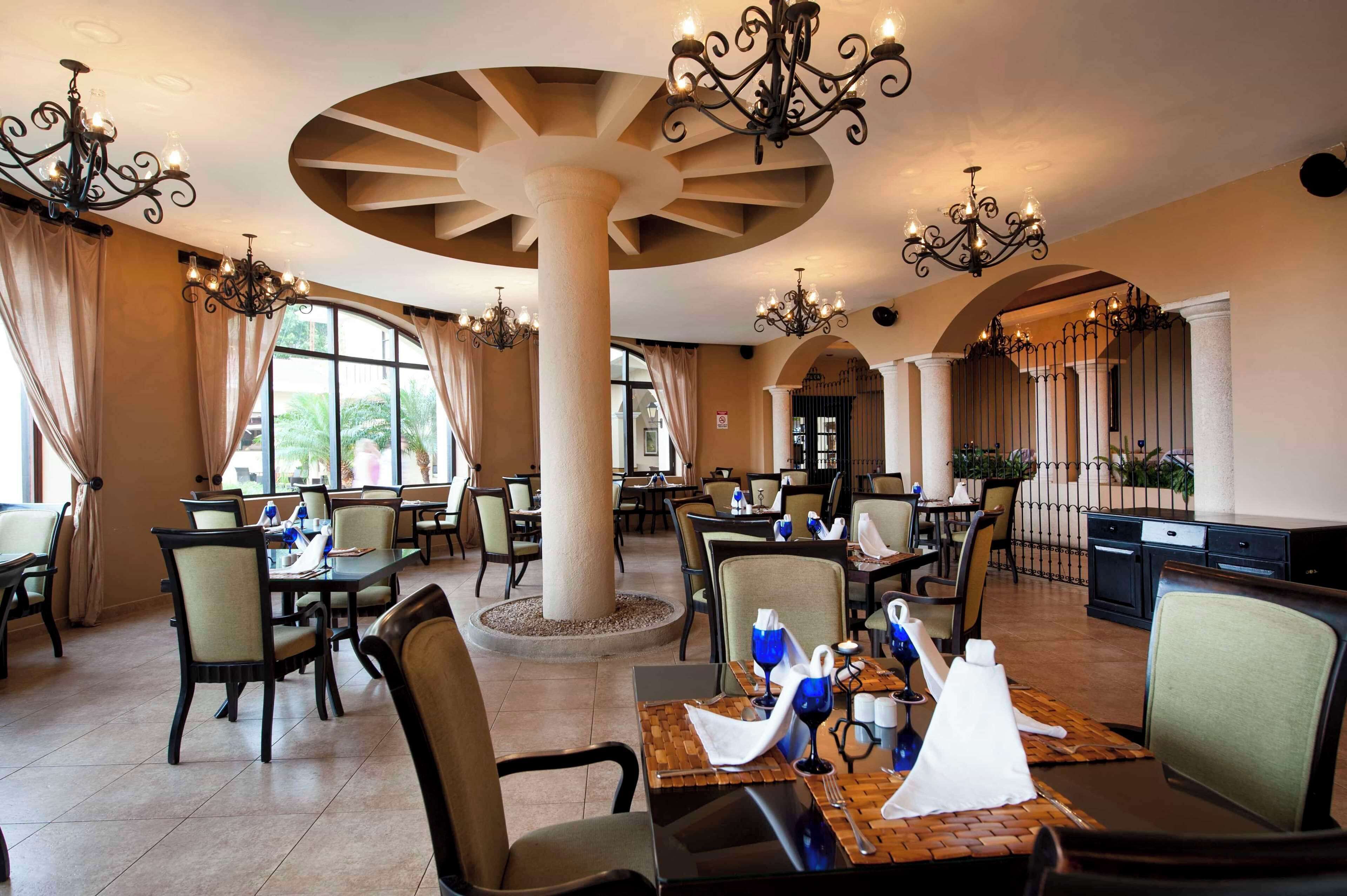 A spacious dining area with multiple tables, chairs, and chandeliers.