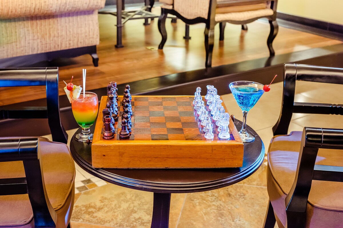 Enjoy a sophisticated stay in this elegant room, featuring a classic wooden chessboard and comfortable seating.