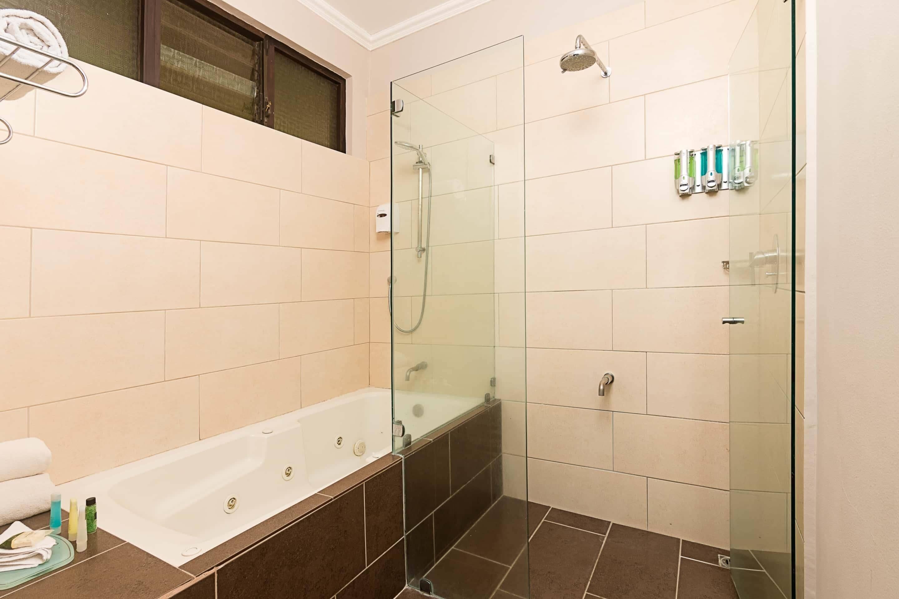 A modern bathroom with a glass-enclosed shower, a bathtub, and a toilet.