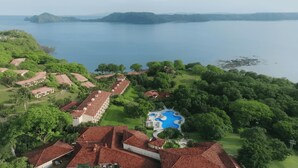 An aerial view of a resort with multiple buildings, a large swimming pool, and lush greenery surrounding a body of water. - Occidental Papagayo - Adults Only - All inclusive (Sardinal)