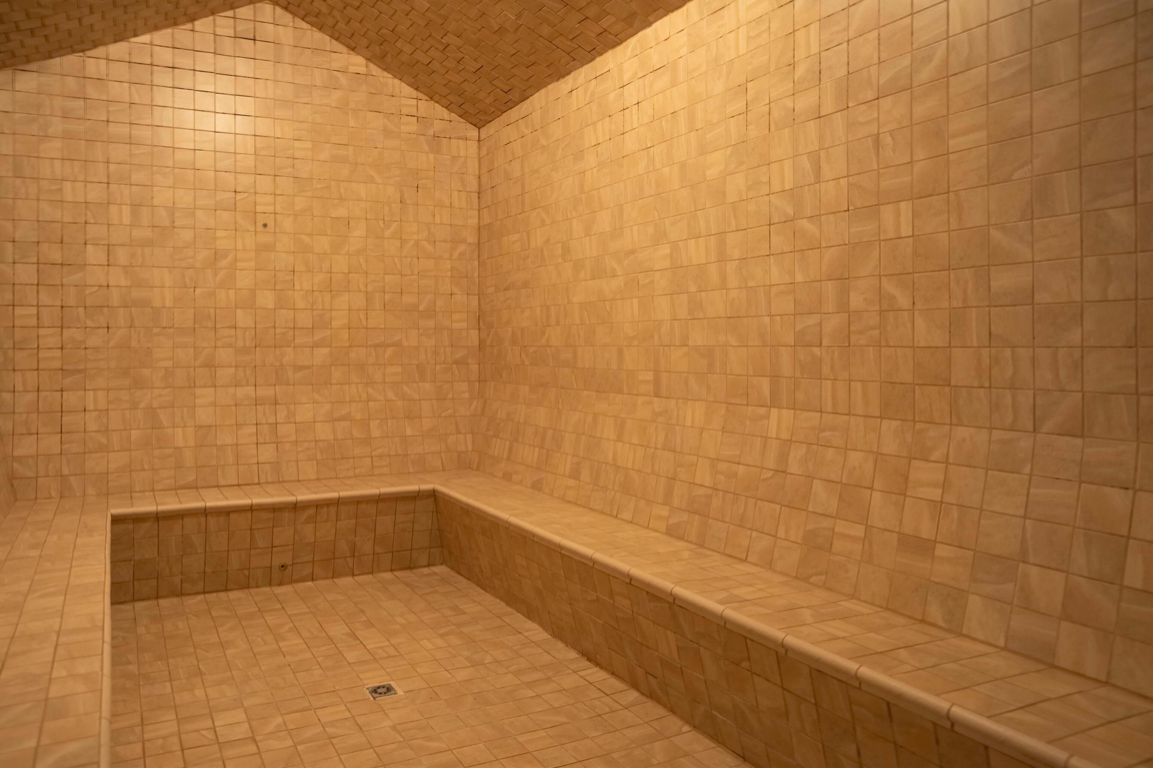 Un baño revestido con azulejos, con un banco y un desagüe.