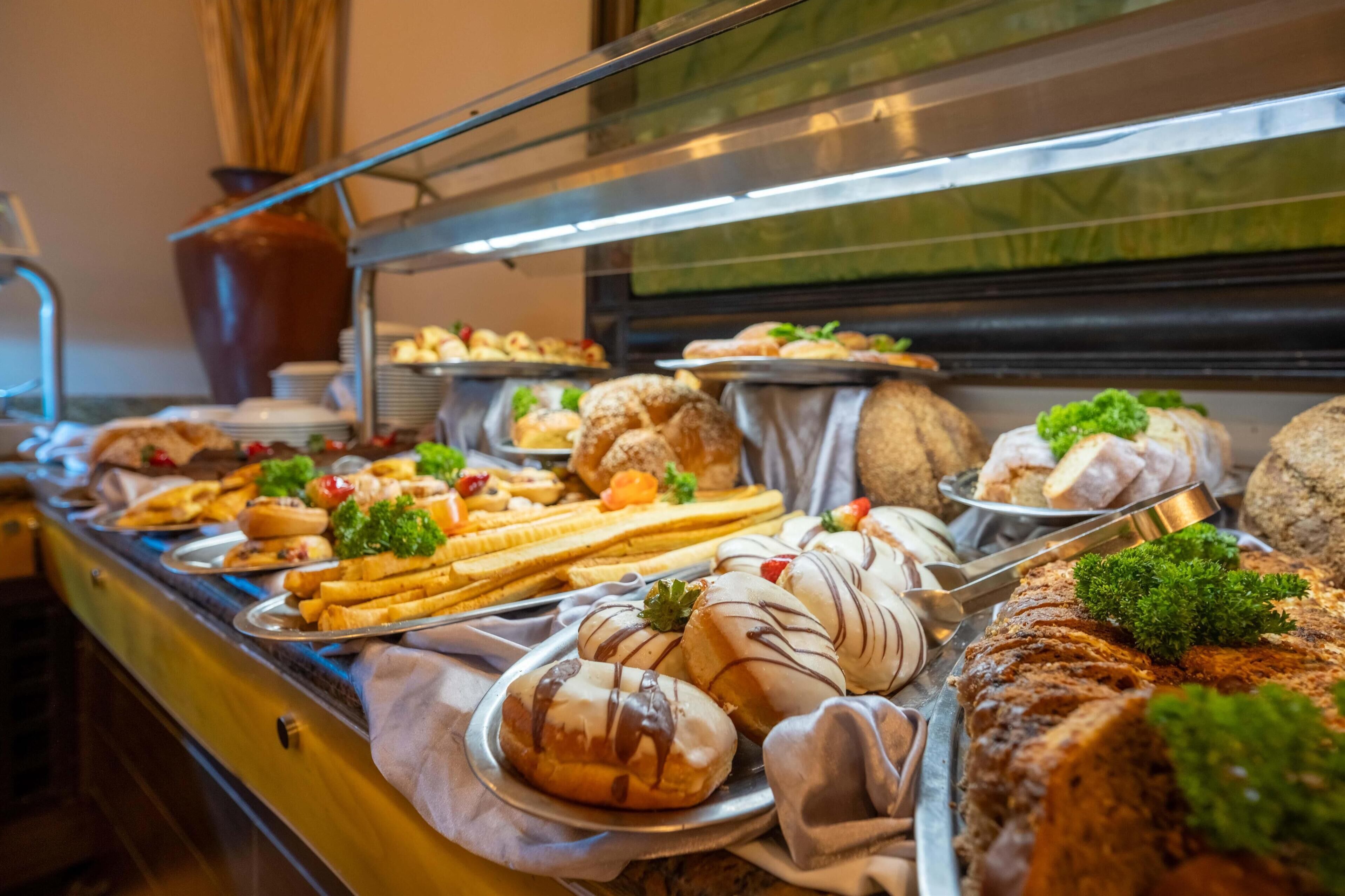 A buffet with various food items including pastries, sandwiches, and salads.