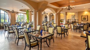 A spacious dining area with multiple tables and chairs, large windows, and decorative chandeliers. - Occidental Papagayo - Adults Only - All inclusive (Sardinal)