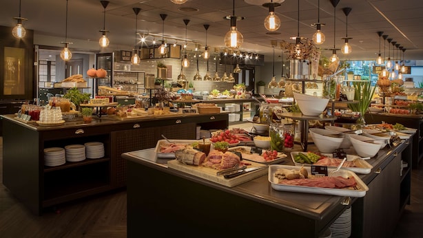 A buffet area with various food items and a kitchen in the background.