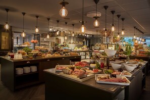 A buffet area with various food items and a kitchen in the background.