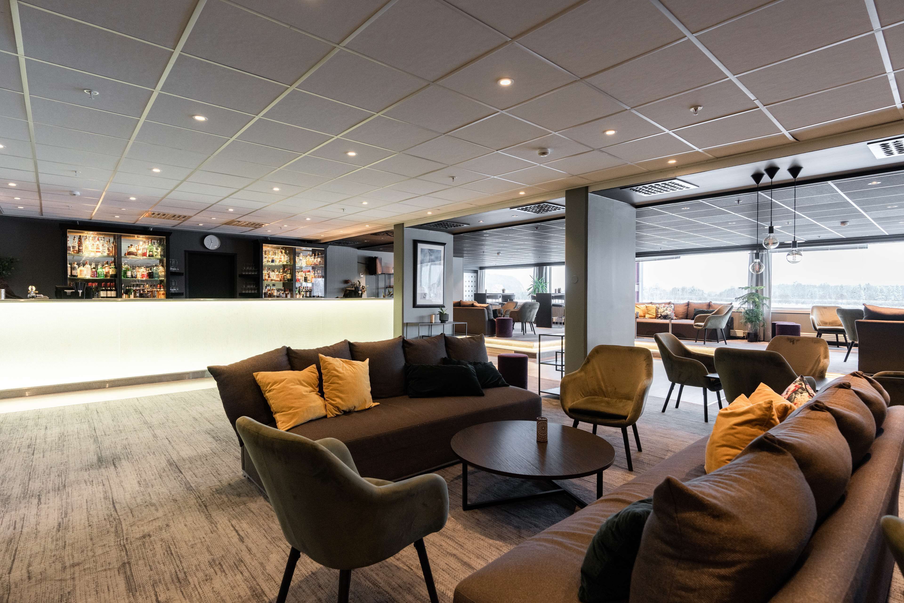A modern lounge area with a bar, sofas, and chairs.