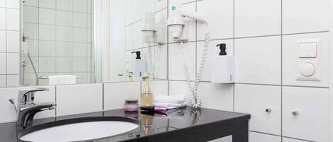 A modern bathroom with a black countertop sink, a large mirror, and a hairdryer mounted on the wall.
