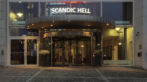 A modern building with a glass entrance and a sign that reads "SCANDIC HELL".