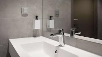 A modern bathroom with a large white sink, chrome faucet, and a mirror reflecting the space.