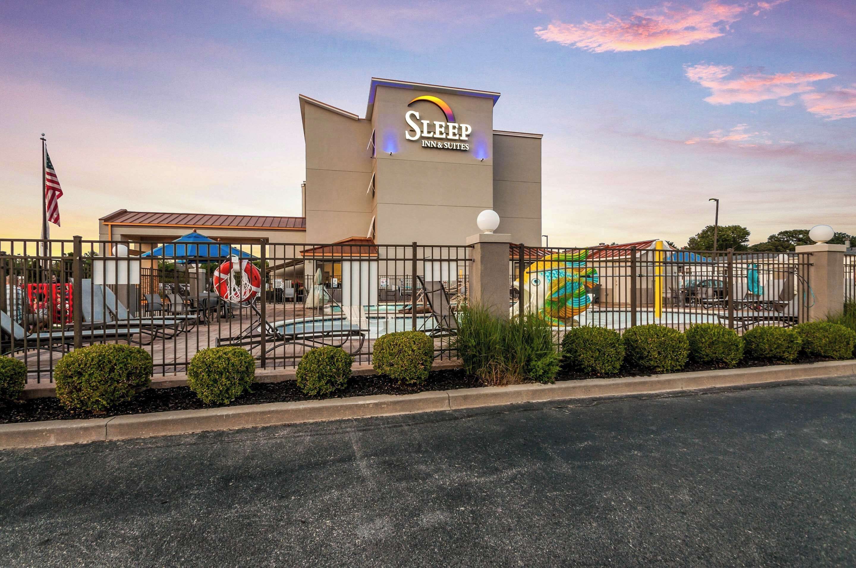 Un hôtel Sleep Inn & Suites doté d’une aire de jeux clôturée et d’un mât sur lequel flotte un drapeau américain.