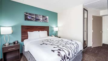 Hotellihuone, jossa on suuri sänky, kaksi yöpöytää valaisimineen, puinen pääty ja turkoosinsävyinen korosteseinä.