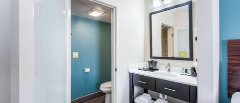 A bathroom with a white sink, dark vanity, and a mirror.
