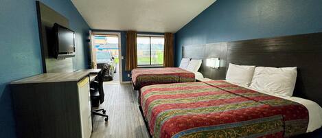 A hotel room with two beds, a desk, and a television.