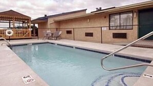 A swimming pool with lounge chairs and a wooden deck. - Knights Inn Greenville, NC (Greenville)