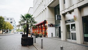 A hotel with a modern facade, a colorful awning, and a sign indicating a restaurant inside. - Kubrat In Helle Mitte (Berlin)