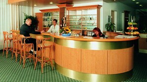 A hotel reception area with a curved counter, wooden chairs, and a green checkered floor. - Kubrat In Helle Mitte (Berlin)