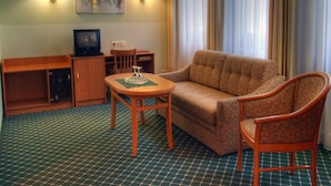 A hotel room with a sofa, armchair, small table, TV, and lamps. - Kubrat In Helle Mitte (Berlin)