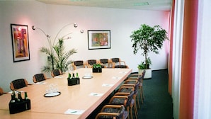 A conference room with a long table, chairs, a potted plant, and artwork on the walls. - Kubrat In Helle Mitte (Berlin)