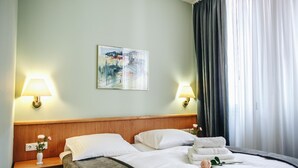 A hotel room with two beds, a wooden headboard, a painting on the wall, and two bedside lamps. - Kubrat In Helle Mitte (Berlin)