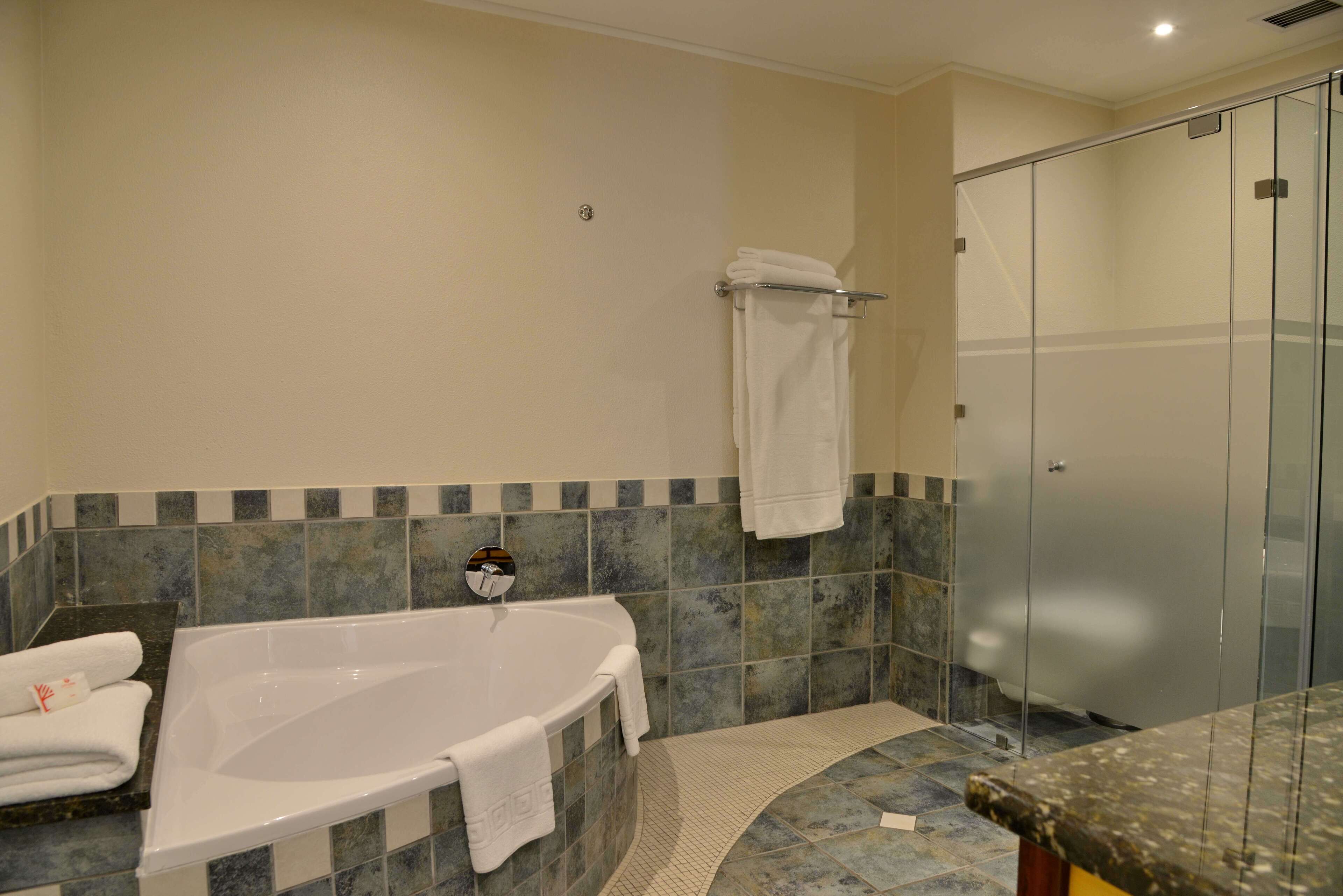 A modern bathroom with a freestanding bathtub, a glass shower enclosure, and a tiled floor.