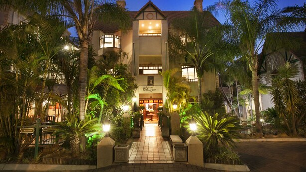 A hotel entrance with a central archway, palm trees, and a sign reading "Courtyard Classic".