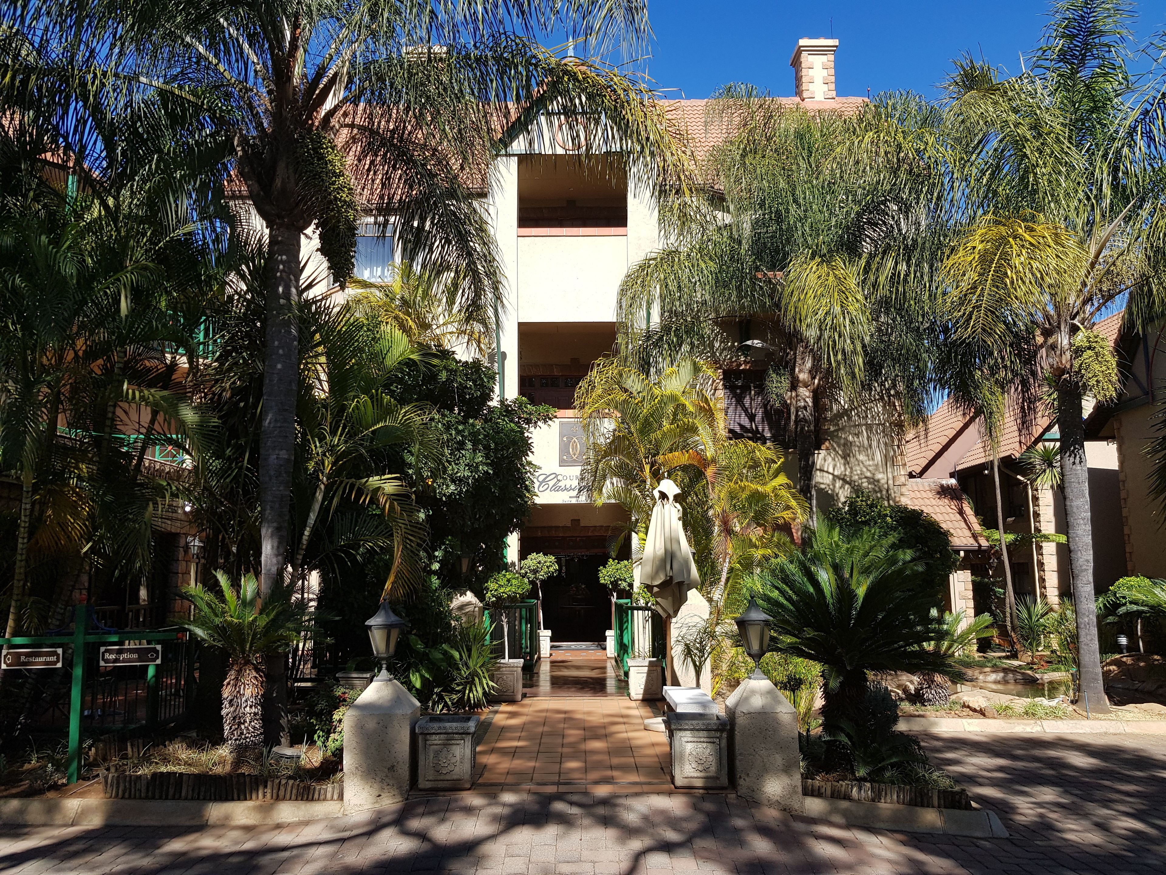 A courtyard with a central pathway leading to a building with a sign reading "Courtyard Classic."