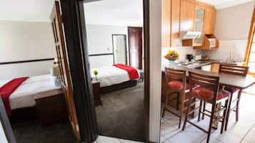 A hotel room with a bed, a desk, and a kitchenette.