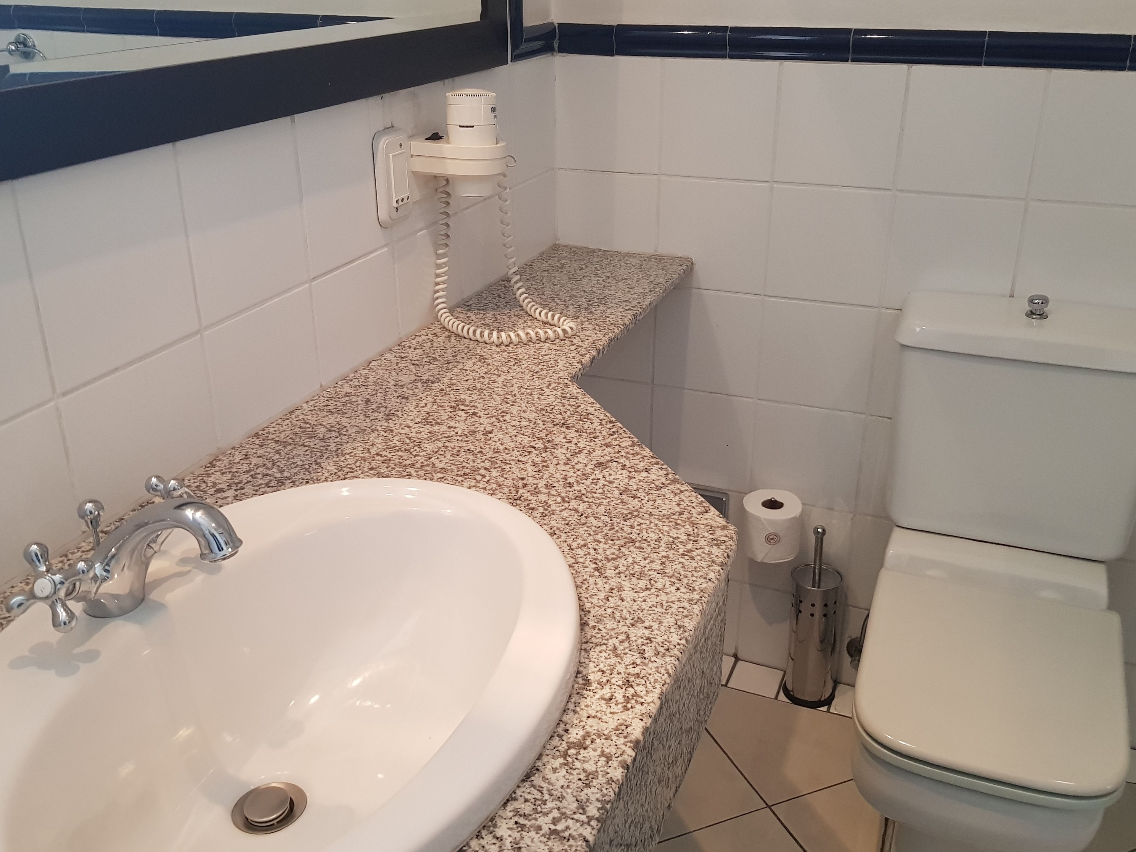 Un bagno con un lavandino bianco, un water e un portasciugamani.