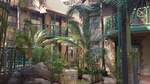 A courtyard with a water feature, palm trees, and a building with a green balcony.