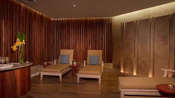 Um espaço de spa com duas poltronas, uma mesinha e um vaso decorativo com flores.