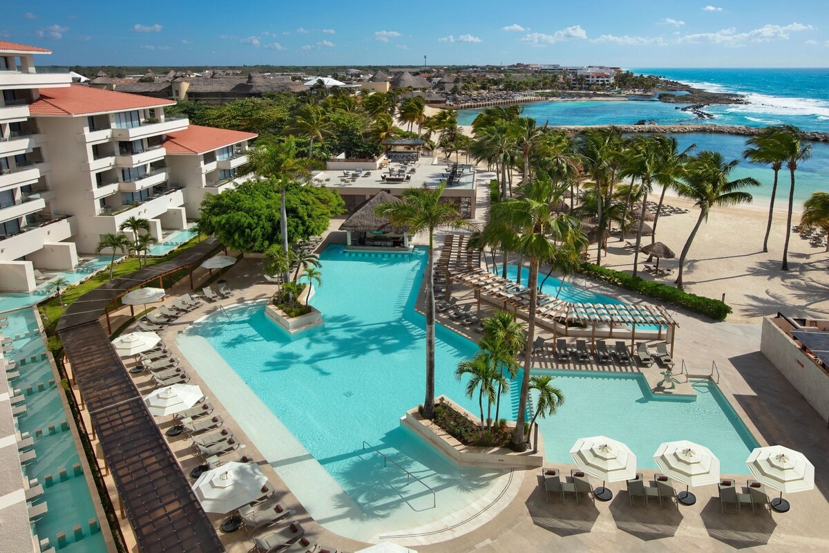 A resort with a large swimming pool, sun loungers, and palm trees. - Dreams Aventuras Riviera Maya - All Inclusive (Puerto Aventuras)