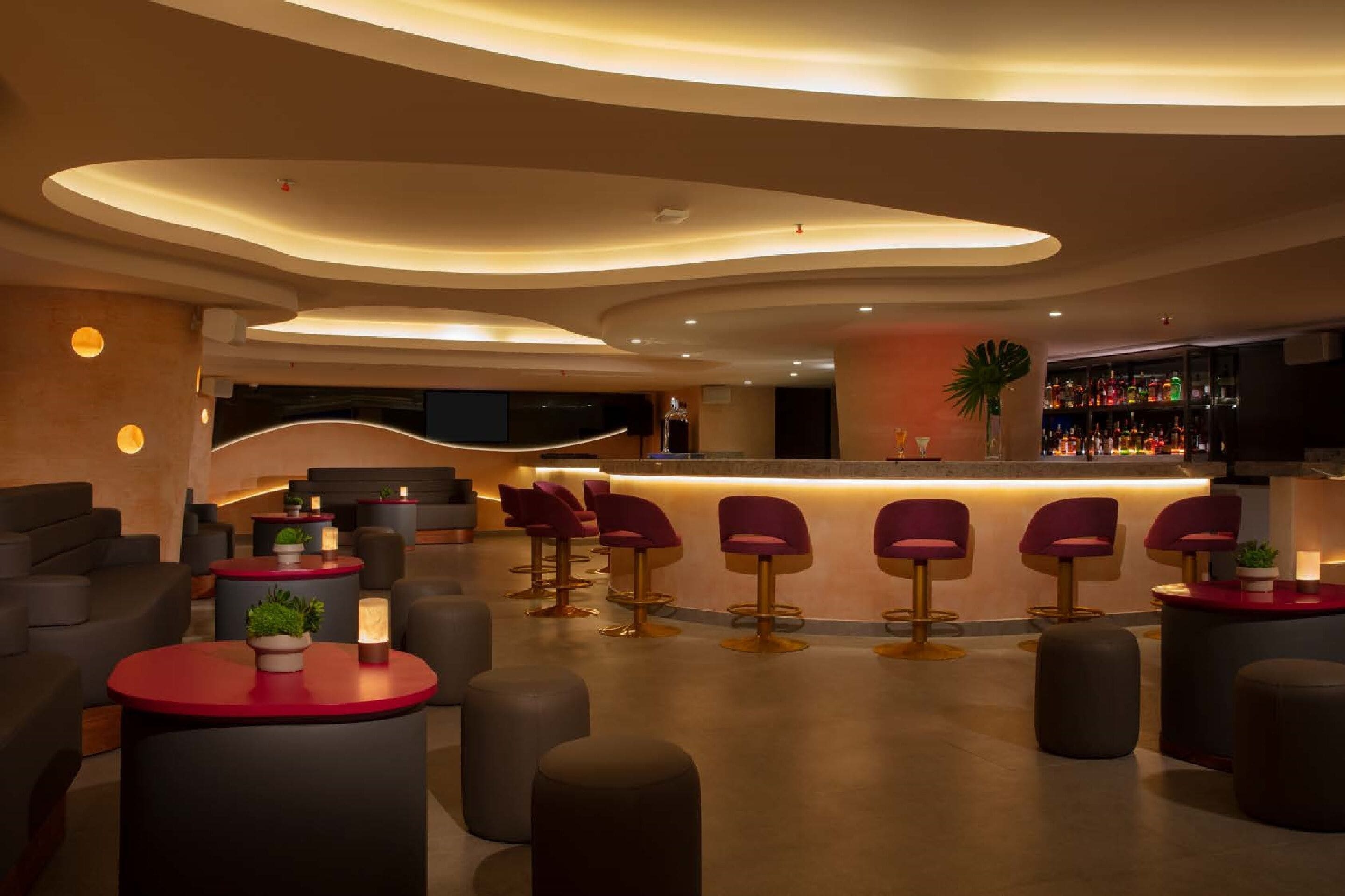 A modern bar area with a curved ceiling, bar stools, and a bar counter.