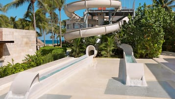 Estructura de toboganes acuáticos con múltiples carriles, zona de piscina y palmeras.